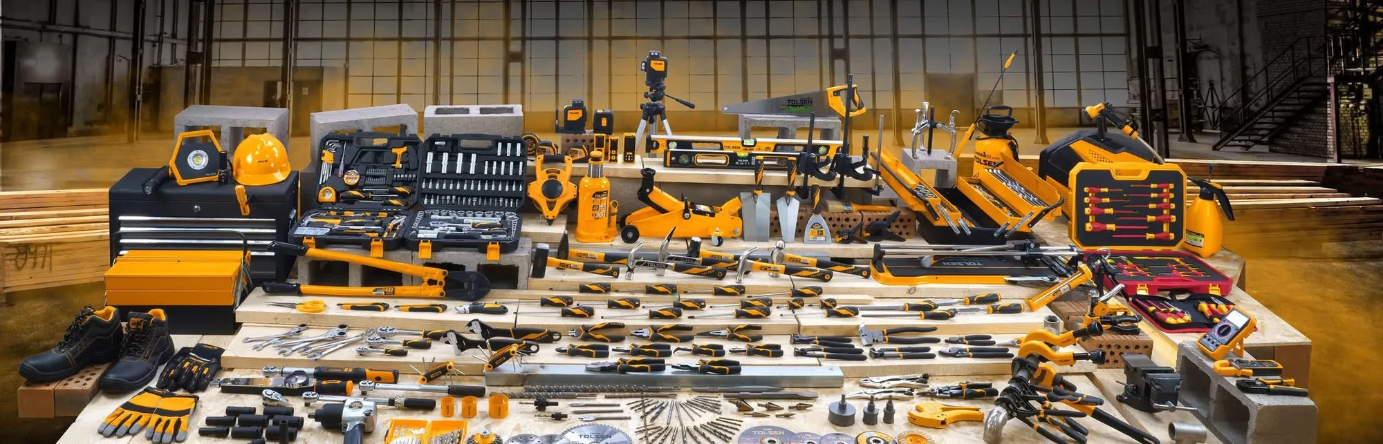 The Tolsen range laid out in a warehouse: hand tools, power tools, jacks, toolboxes and safety gear